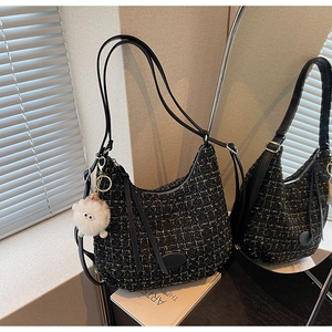 Detail of black tweed shoulder bag with leather strap and plush monster pendant decor