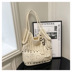 Detailed close-up of beige crochet tote bag featuring wooden beads and long fringe tassels