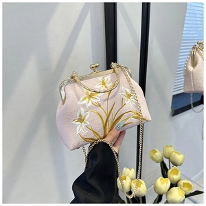 Close-up of pink satin evening clutch with white lily embroidery and gold metal clasp