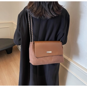Close-up of model wearing a vintage two-tone brown leather shoulder bag with gold chain strap