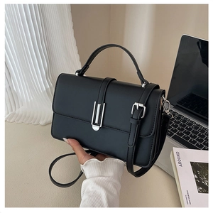Close-up of a black structured crossbody bag featuring silver metal lock and top handle