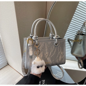 Silver marble pattern handbag detail showing knotted handles and plush monster charm
