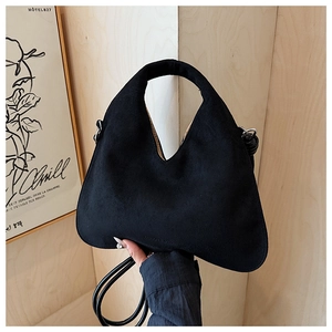 Close-up of black matte suede shoulder bag with V-shaped top and curved handle