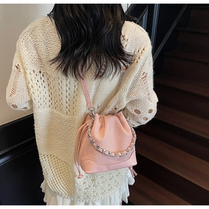 Pink bucket bag with diamond quilted texture and metal chain detail on model