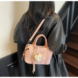 Detail of pink Boston bag with fuzzy bear charm and tassel on a stylish black jacket