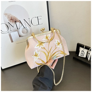 Close-up of pink floral embroidery and gold metal handle on a retro cheongsam handbag
