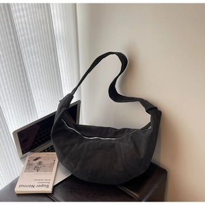 Detail of black crescent canvas bag with pleated seams and wide shoulder strap