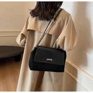 Detail of black patchwork leather shoulder bag with silver chain and metal brand plate
