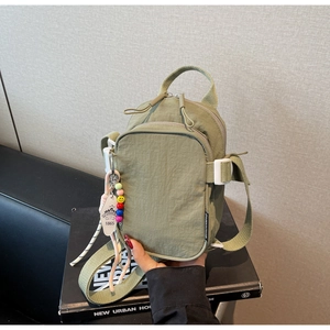 Olive green nylon crossbody bag detail with double zippers and smiley face charm