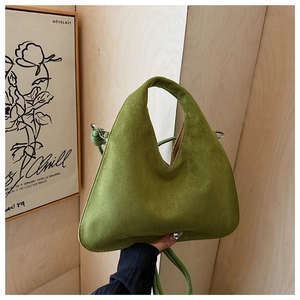 Detail view of avocado green frosted leather dumpling bag with top handle and shoulder strap