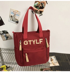 Detail of burgundy canvas tote bag with GTYLF patch and multiple zipper pockets