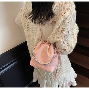 Detail of pink drawstring bucket bag with mesh weave texture and silver chain strap