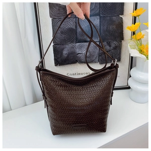 Macro detail of dark brown woven checkerboard texture and metal logo on bucket bag