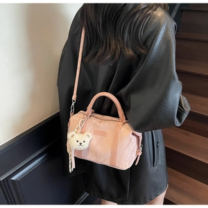 Detail of pink nylon boston bag with plush bear charm and crossbody strap