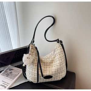 Detail of tweed shoulder bag with gold threads, plush charm and black leather strap