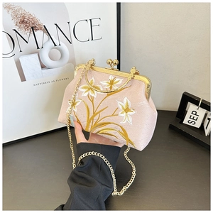 Close-up of vintage pink embroidered handbag with golden floral patterns and beaded clasp