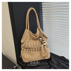 Close-up of beige crochet tote bag with dark beads and a large wood bead tassel detail
