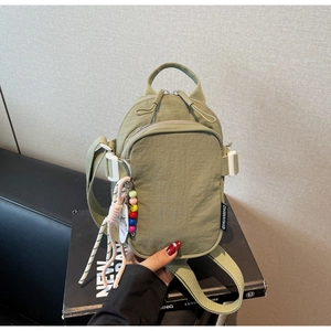 Detail view of olive green nylon crossbody bag showing the front pocket and logo label