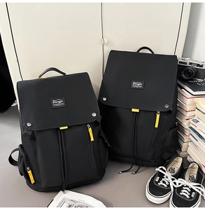 Detail of black canvas backpack with yellow contrast zippers and drawstrings next to books