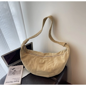 Detail of a beige suede croissant bag with radial quilted pleats and a metal zipper