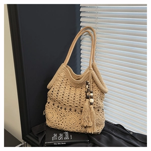 Detail of bohemian hand-woven tote bag with decorative tassels and wooden beads