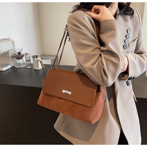 Detailed close-up of brown patchwork shoulder bag with silver chain strap and metal buckle