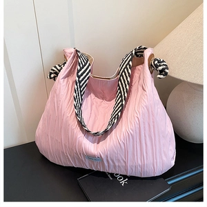 Détail du sac fourre-tout plissé rose clair avec bandoulière à rayures noires et blanches