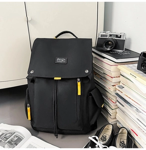 Detail of black canvas backpack with yellow pull tabs and drawstring closure on books
