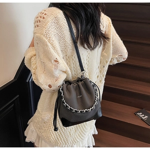 Detail of drawstring bucket bag with silver chain and leather strap on a model