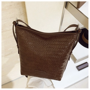Close-up of deep brown woven bucket bag featuring detailed leather texture and silver buckle