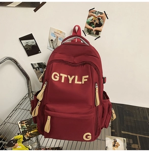 Detail of burgundy school backpack with yellow GTYLF applique on a metal shelf display