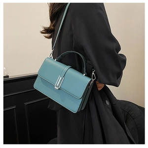 Detail of light blue faux leather handbag featuring silver clasp and adjustable strap