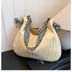 Détail du sac fourre-tout plissé jaune clair avec bandoulière à rayures noires et blanches