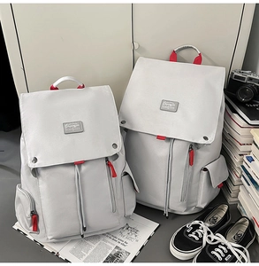 Close-up of gray canvas backpacks in two sizes with red accents and buckle detail