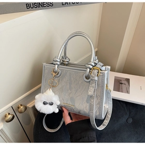 Detail of silver metallic tote bag with marble pattern and fluffy white monster charm