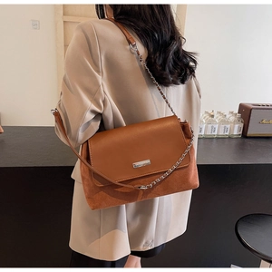 Detail of caramel brown underarm bag showing smooth leather and suede texture contrast