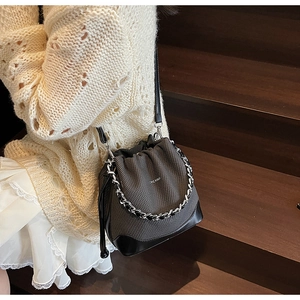 Detail showing charcoal grey bucket bag with drawstring closure and silver chain strap