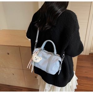 Lifestyle view of light blue pillow bag with plush bear charm on a crossbody strap