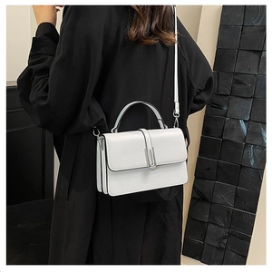White leather handbag on black coat showing crossbody style and metal clasp detail