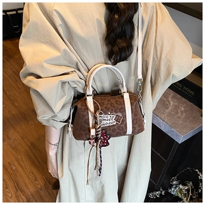 Details einer braunen Boston-Tasche mit Leopardenmuster, weißen Griffen und Umhängegurt