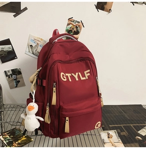 Detail of burgundy waterproof nylon backpack with GTYLF embroidery and duck plush charm