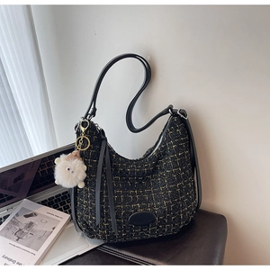 Close-up of black tweed hobo bag with gold metallic threads and white plush sheep pendant
