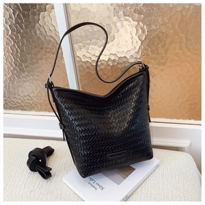 Close-up of black woven leather bucket bag with metallic logo and adjustable strap