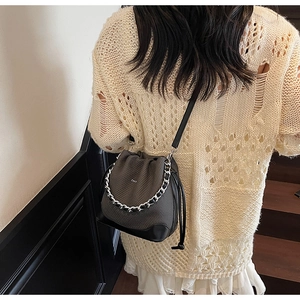 Detailed view of the textured grey drawstring bucket bag with silver chain on model