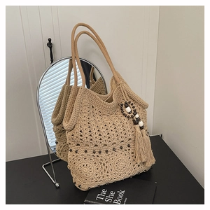 Detail of beige hand-woven tote bag with bohemian knit patterns and wooden tassel charm