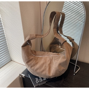 Detail of dark brown dumpling bag in matte suede with silver zipper and wide strap