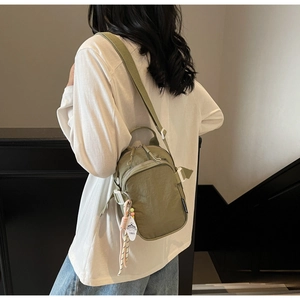 Olive green nylon crossbody bag with layered zippers and wide adjustable shoulder strap