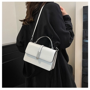 Minimalist white leather crossbody bag with silver buckle worn by a model in black