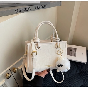 Detail of white PU leather tote bag featuring wrinkled texture and plush charm accessory