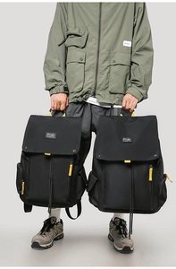 Detail of durable black canvas travel backpacks with flap-top drawstring and yellow cords